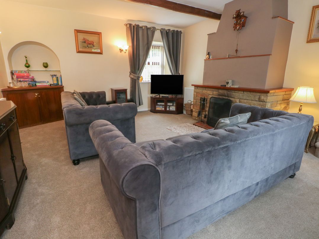 A living room with sofas and a television at West End House in Thornton, West Yorkshire