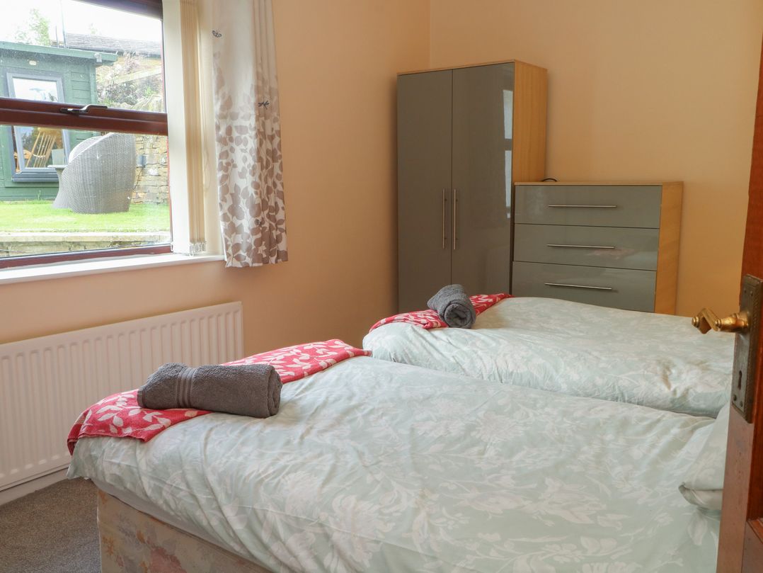 A bedroom with two beds and a wardrobe at West End House in Thornton, West Yorkshire