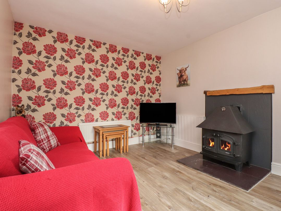 A living room with a sofa and fireplace at The Farmhouse in Brynsiencyn near Newborough