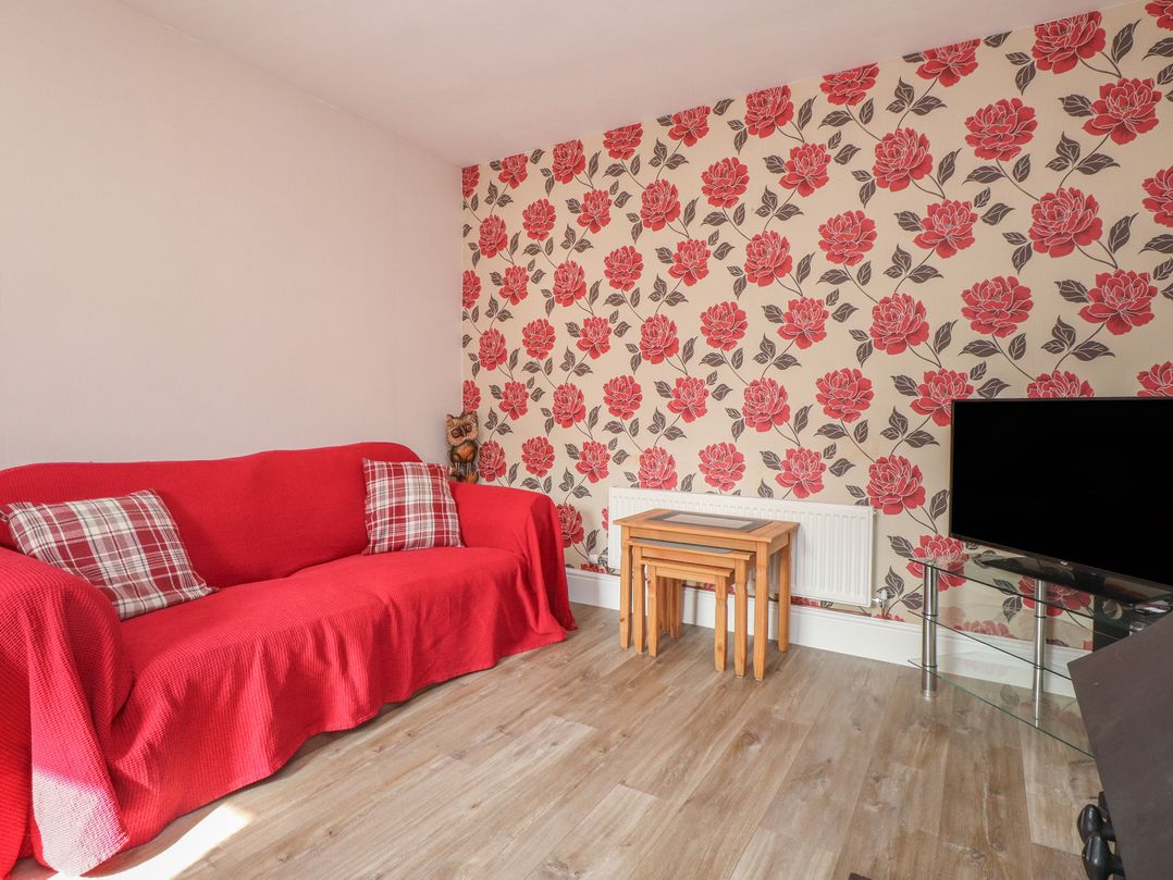 A living room with a red sofa and coffee table at The Farmhouse in Brynsiencyn near Newborough