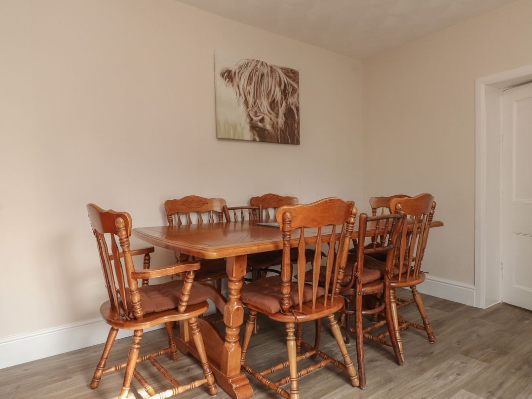 A dining room with a wooden table and chairs at The Farmhouse in Brynsiencyn near Newborough