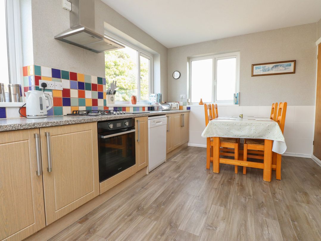 A kitchen with appliances and a table at The Farmhouse in Brynsiencyn near Newborough