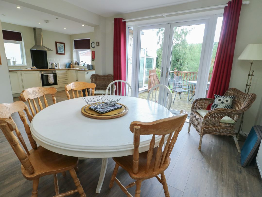 A dining room with a round table and chairs at Awelon in Rhos-On-Sea