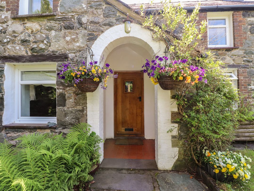 An exterior entrance with a door and hanging baskets at Plas Mawr in Groeslon
