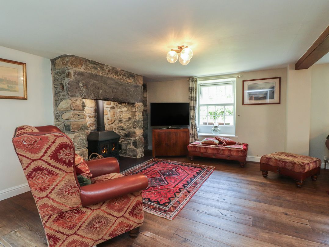 A living room with a fireplace and seating at Plas Mawr in Groeslon