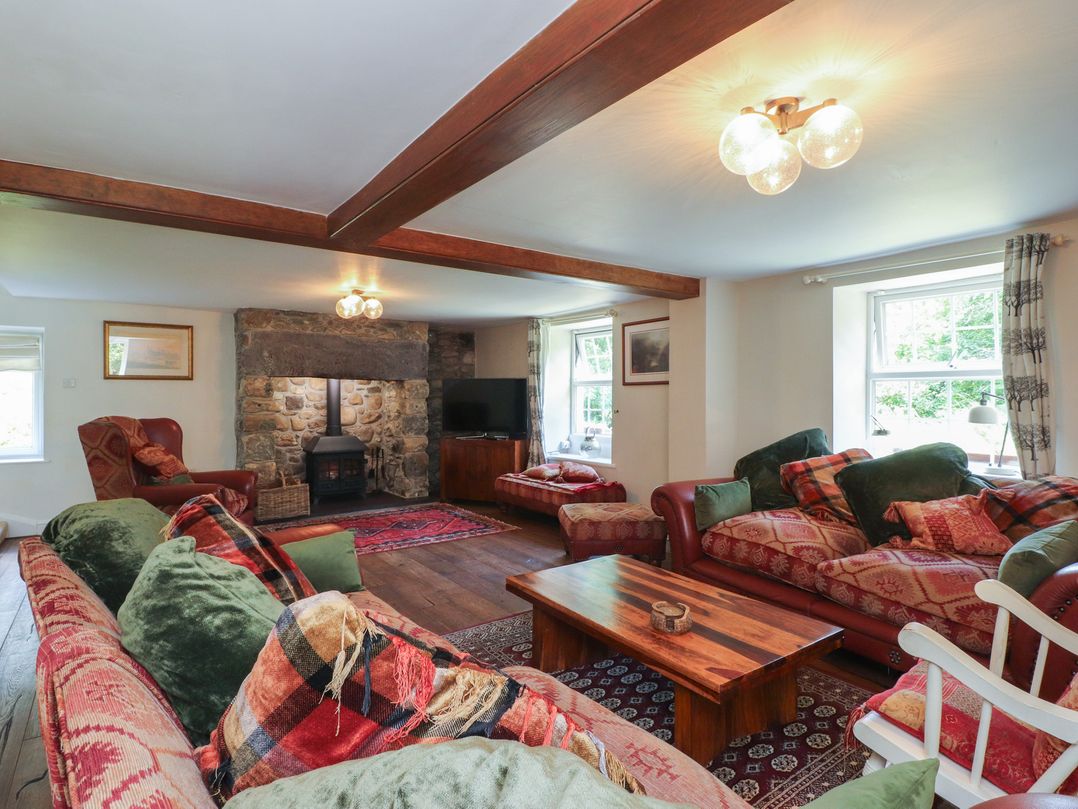 A living room with a fireplace and television at Plas Mawr in Groeslon