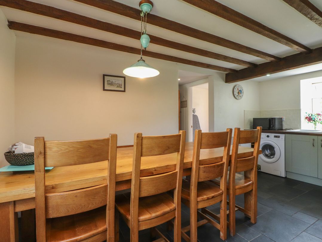 A kitchen with a wooden dining table and chairs at Plas Mawr Groeslon