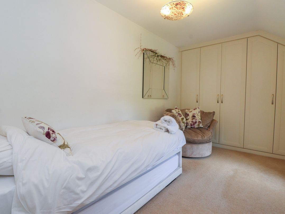 A bedroom featuring a bed, a cushion, a mirror, and a wardrobe at Plas Mawr in Groeslon