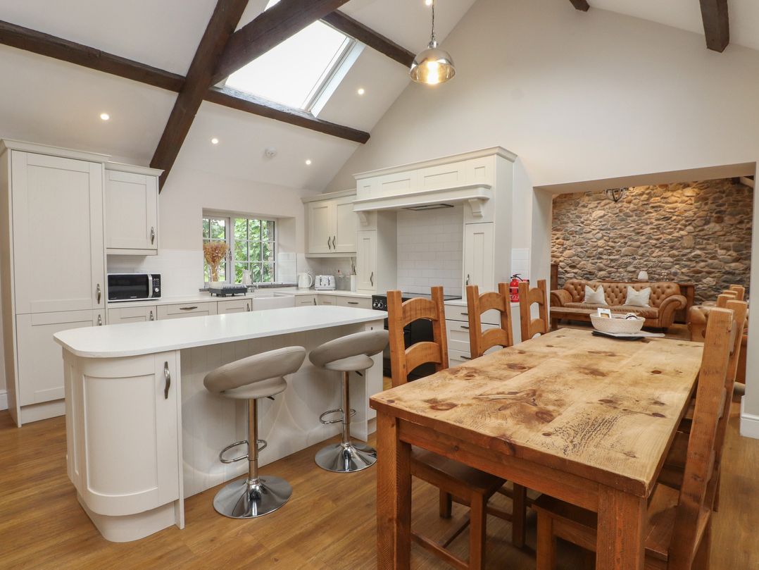 A kitchen with a wooden table and chairs at Beudy'r Wennol in Groeslon