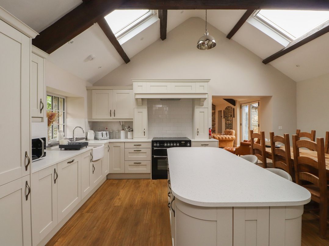 A kitchen with cabinets and appliances at Beudy'r Wennol Groeslon