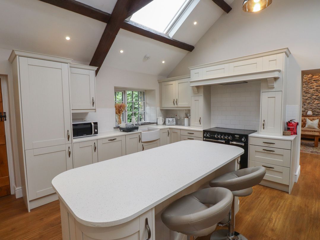 A kitchen with an island, microwave, and sink at Beudy'r Wennol Groeslon