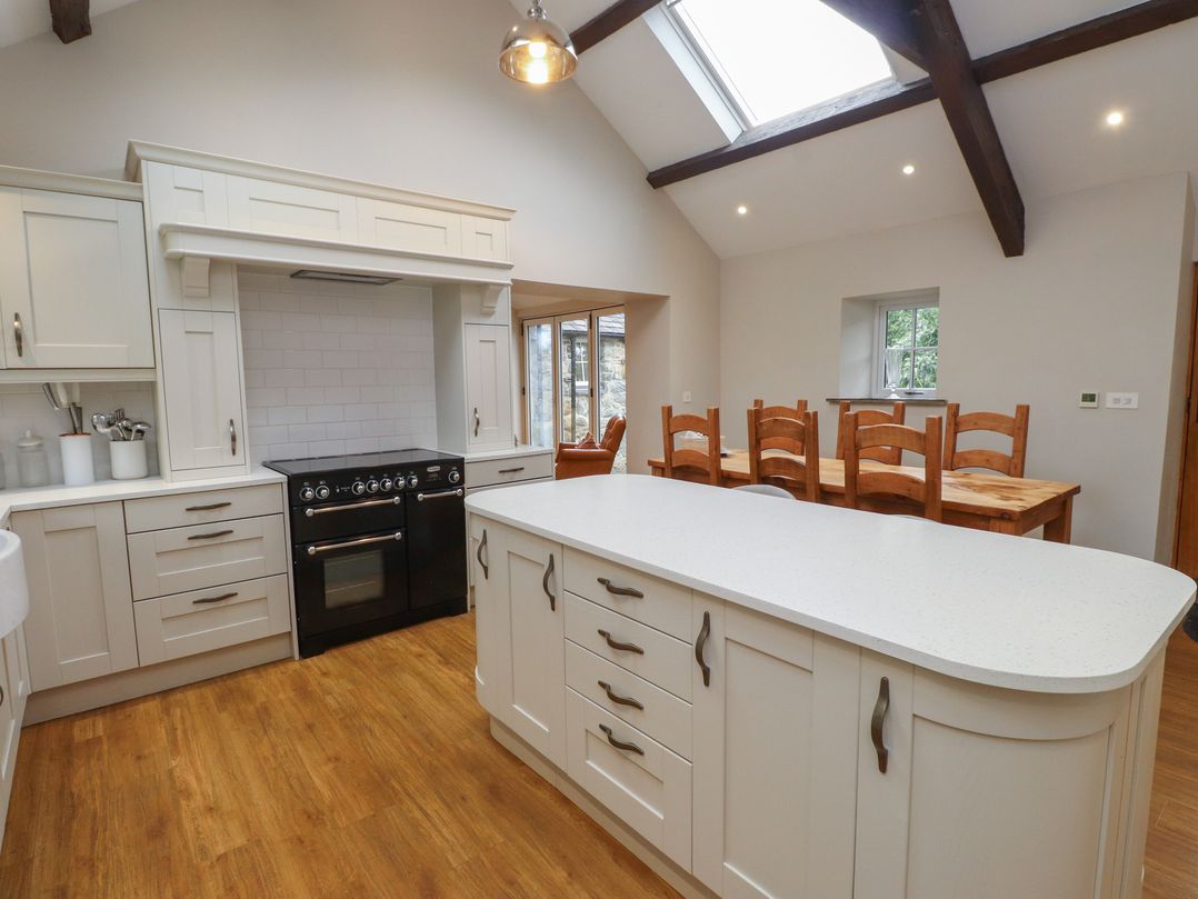 A kitchen with an island and dining table at Beudy'r Wennol Groeslon
