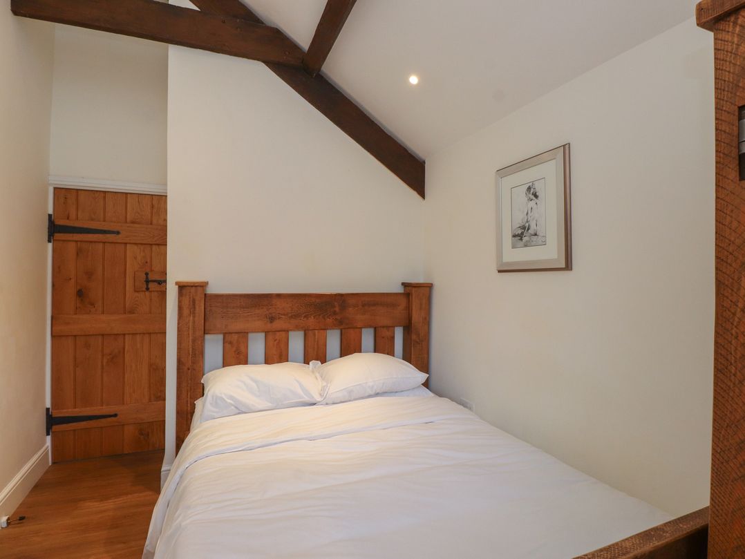 A bedroom with a bed and wooden door at Beudy'r Wennol in Groeslon