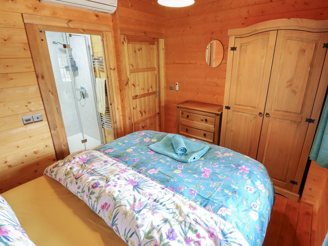 A bedroom with a bed and shower at Tythe Lodge – Hot Tub Retreat in Rural Lincolnshire | Family-Friendly Lodge Near Heckington