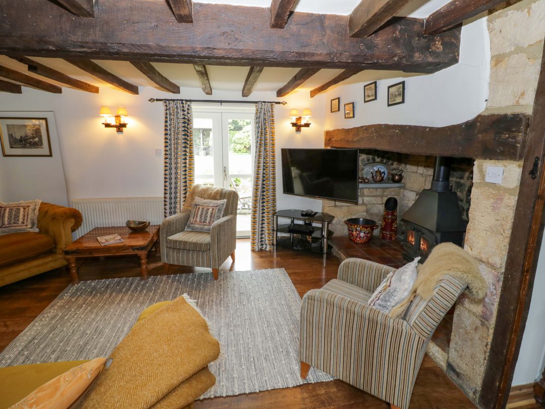 A living room with a sofa, armchair, and television at Elmhurst Cottage, Lower Quinton