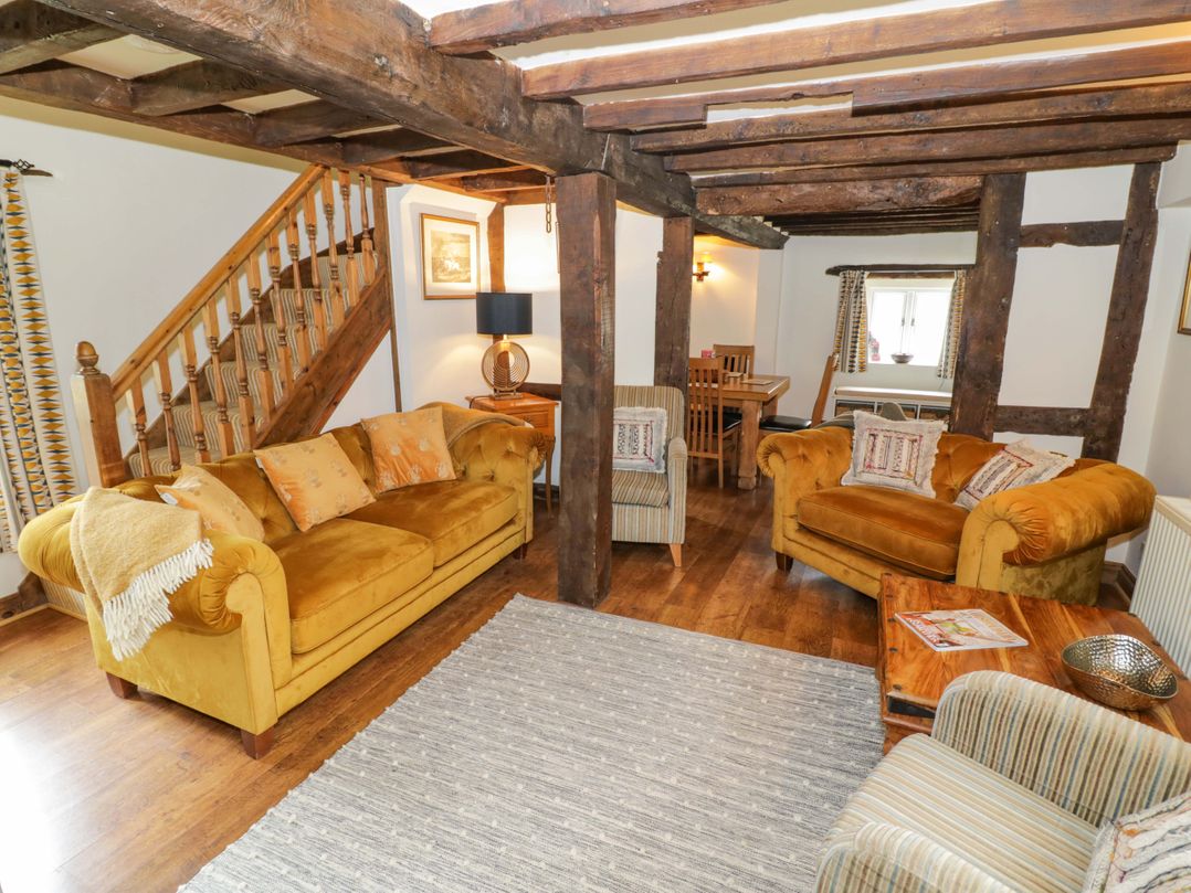 A living room with a sofa and dining table at Elmhurst Cottage in Lower Quinton