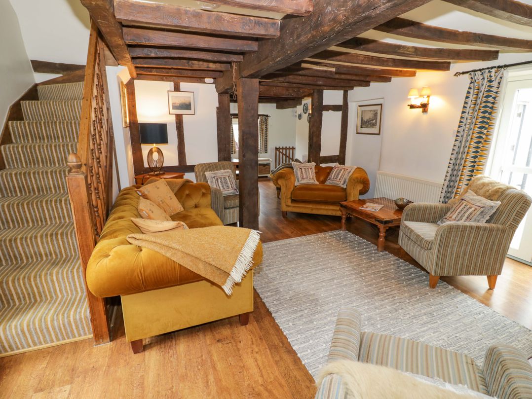 A living room with sofas and a staircase at Elmhurst Cottage in Lower Quinton