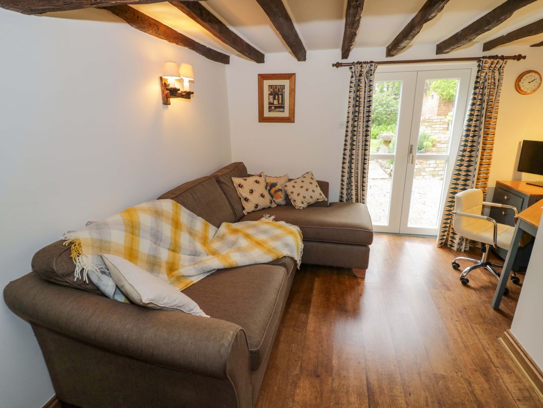 A snug with a sofa and desk at Elmhurst Cottage in Lower Quinton