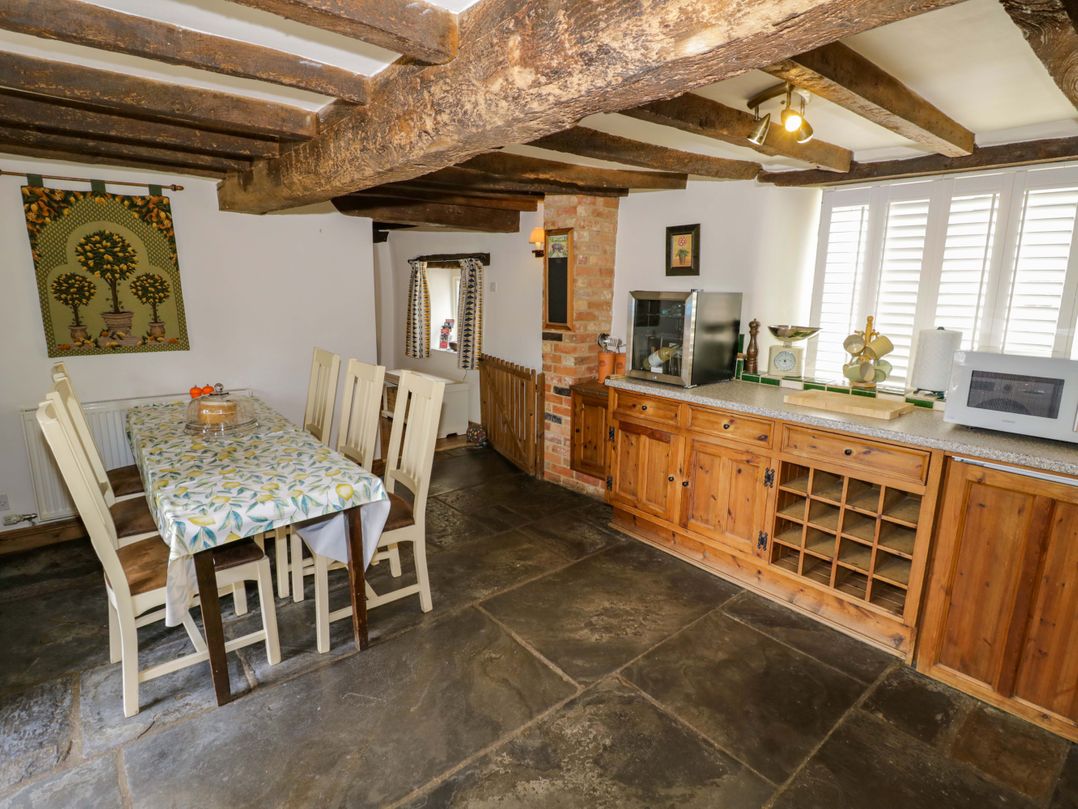 A kitchen with a dining table and cabinets at Elmhurst Cottage in Lower Quinton