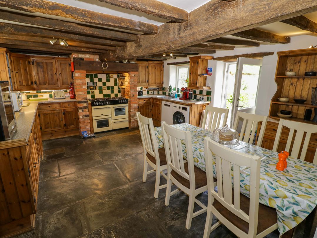 A kitchen with wooden cabinets and a dining table at Elmhurst Cottage in Lower Quinton