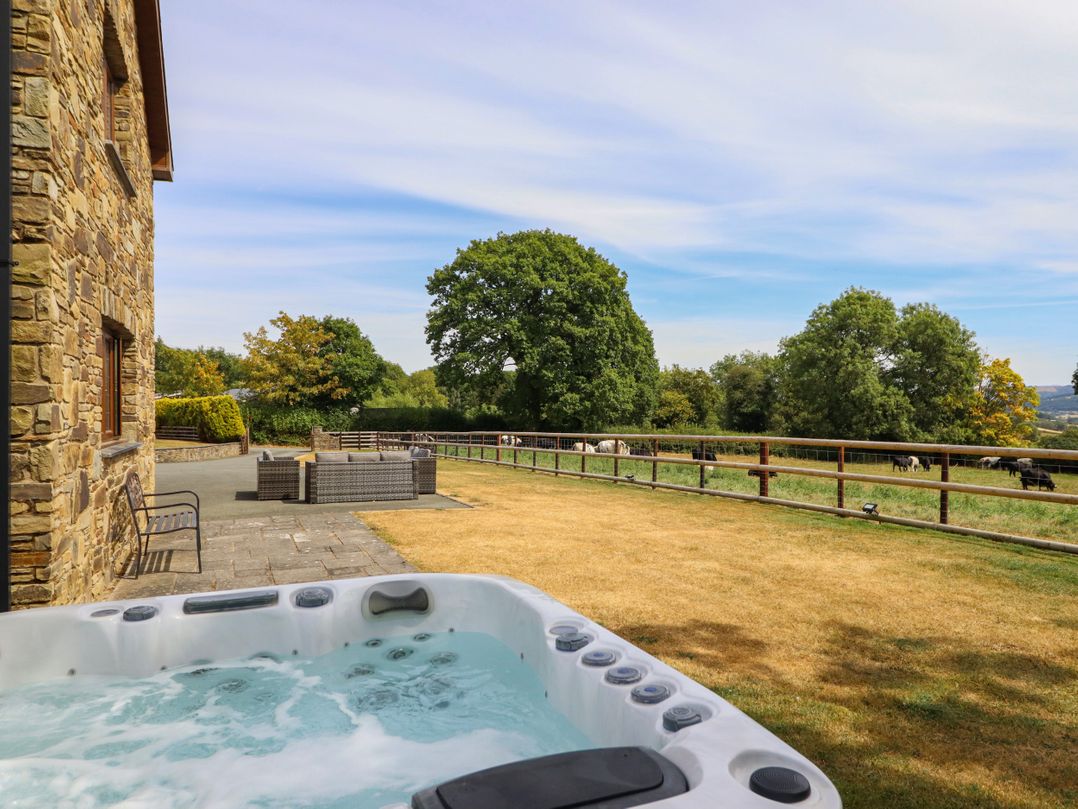 An outdoor area with a hot tub and seating at Ty Berllan in Caersws