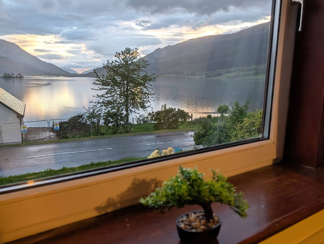 A window view overlooking a lake and mountains at Callart View in Glencoe