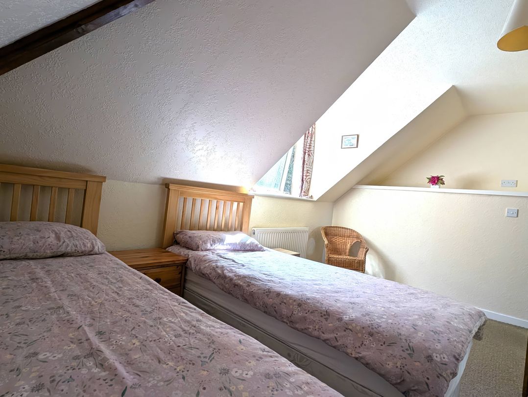 A bedroom with two beds and a chair at Callart View in Glencoe