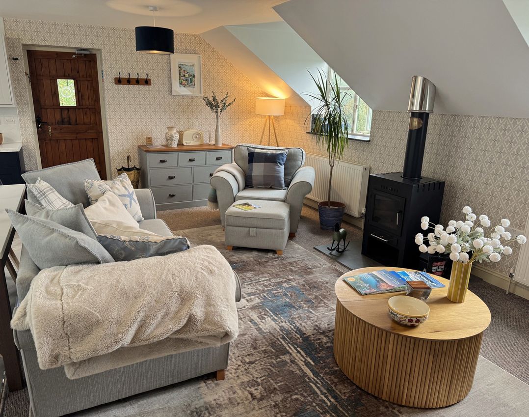A living room with a sofa and armchair at The Hayloft in Lostwithiel