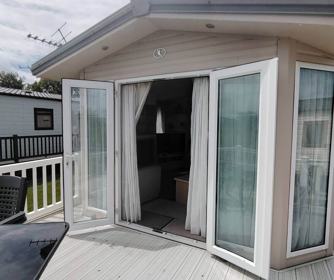 A sunroom with double doors leading outside at Marine Holiday Park - 21NC in Kinmel Bay