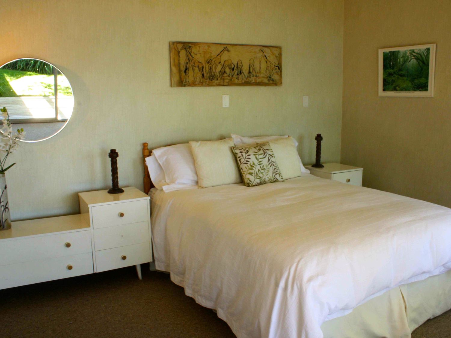 A bedroom with a large bed white bedding bedside tables with lamps and wall art at Moeroa - Wharewaka Holiday Home in Wharewaka