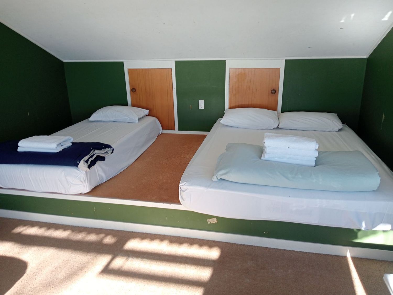 A bedroom with two beds and folded towels on them at Moeroa - Wharewaka Holiday Home in Wharewaka