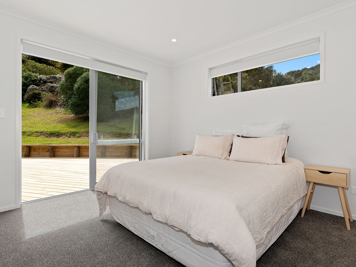 A bedroom with a bed and two nightstands next to sliding glass doors leading outside at The Platinum Rendezvous - Matapouri Holiday Home in Matapouri