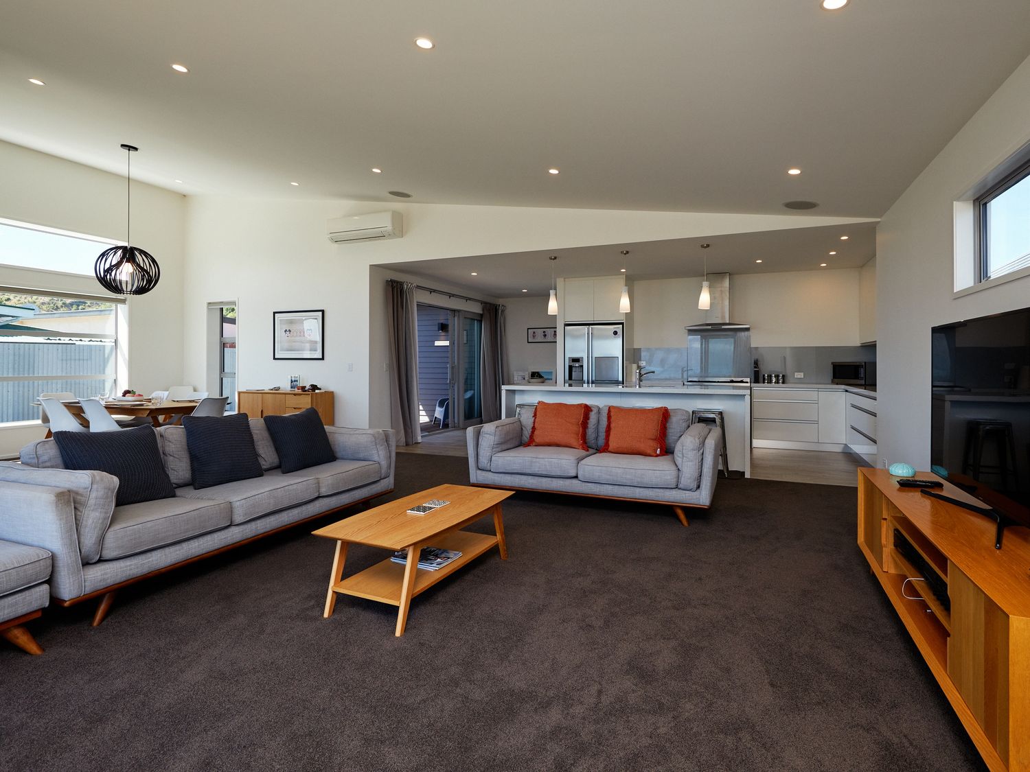 A living room with two sofas and a wooden coffee table facing a TV stand at The Kaikoura Bach Retreat in Kaikoura
