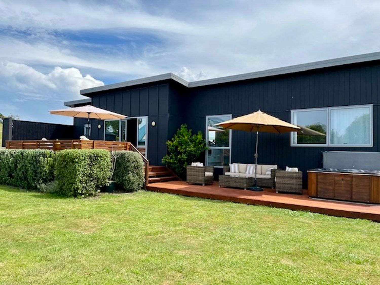 An outdoor area with seating and a hot tub at SeaRenity - Waimarama Holiday Home Waimarama