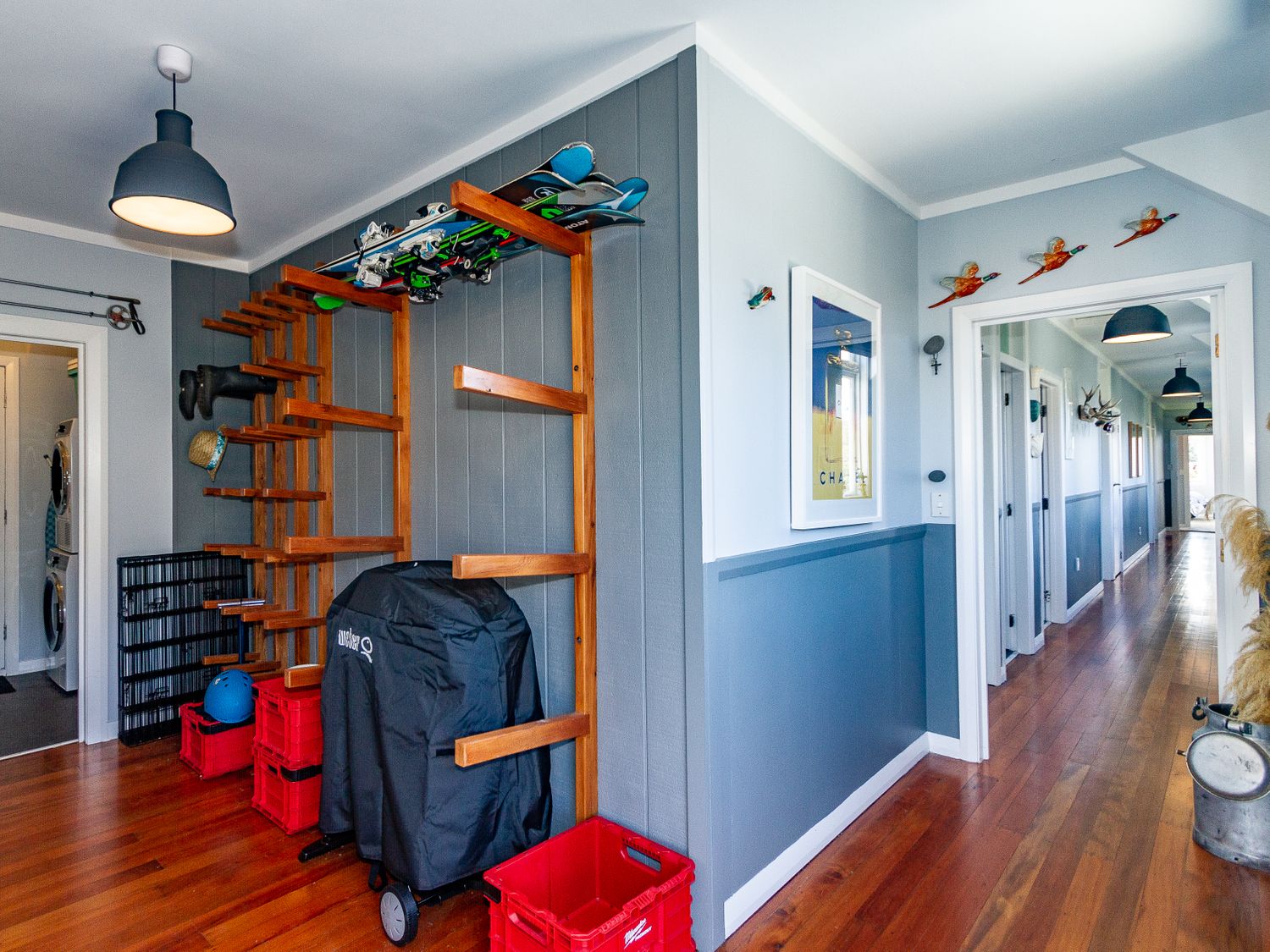 A hallway with wooden flooring and blue walls featuring storage racks holding skis and boots at Ohakune Barracks Ohakune