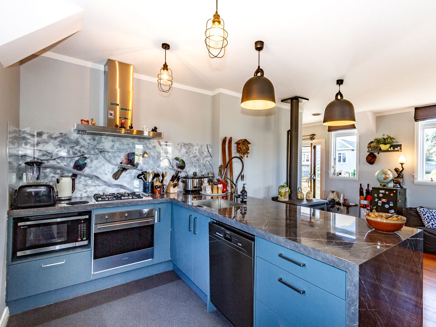 A kitchen with blue cabinets a gray marble countertop and a backsplash with bird designs at Ohakune Barracks in Ohakune