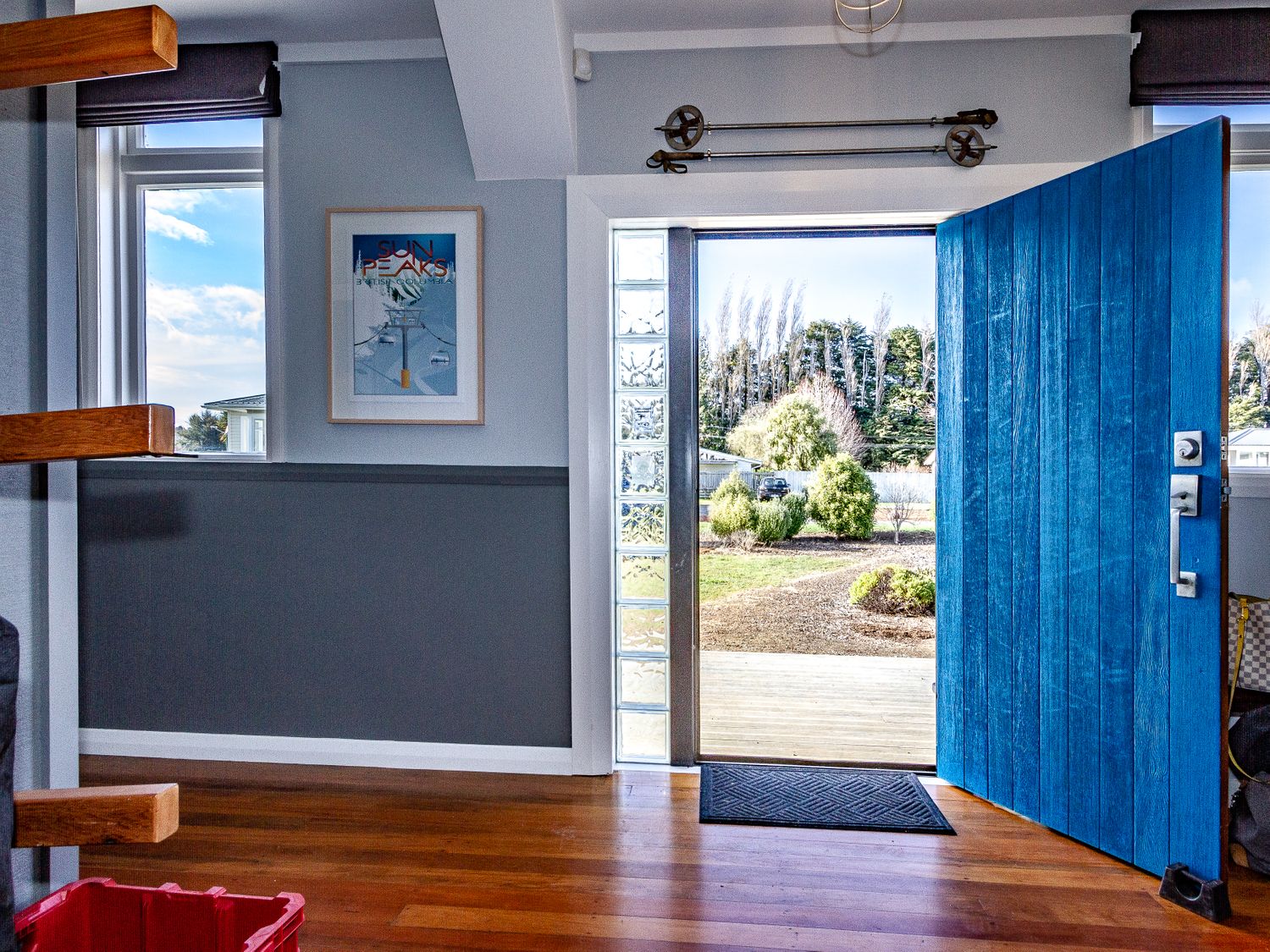 An interior room with an open blue front door showing a view of a garden with bushes and trees at Ohakune Barracks in Ohakune