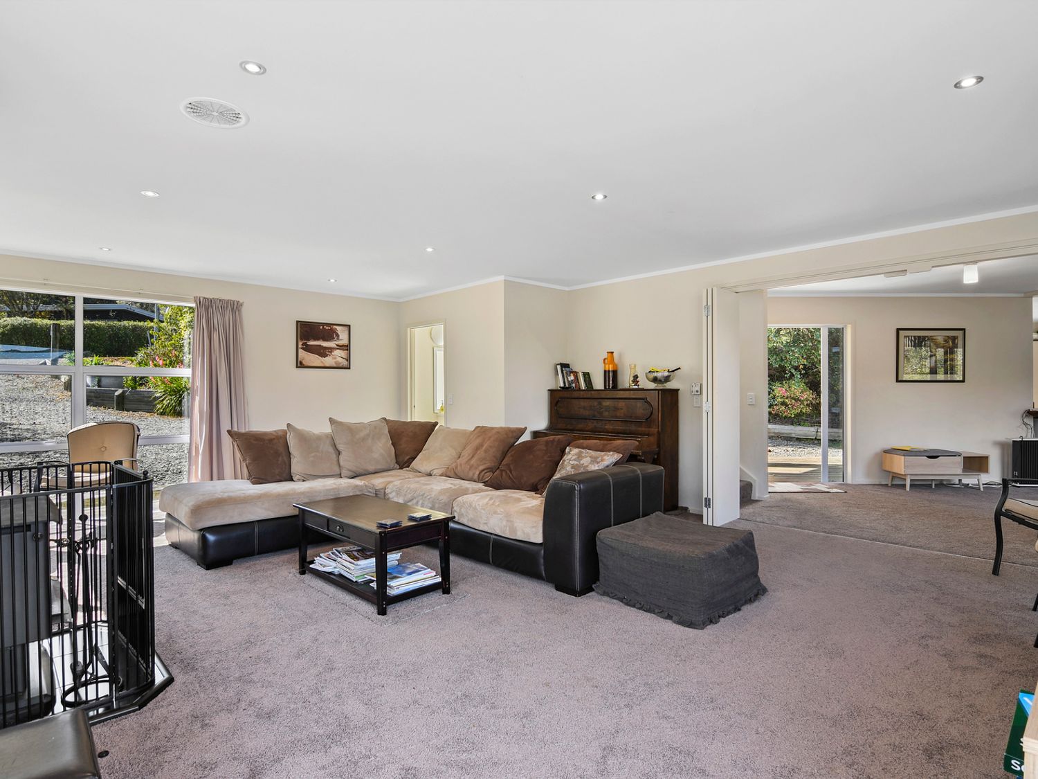 A living room with a sectional sofa coffee table piano and sliding doors at Millard House - Marlborough Sounds