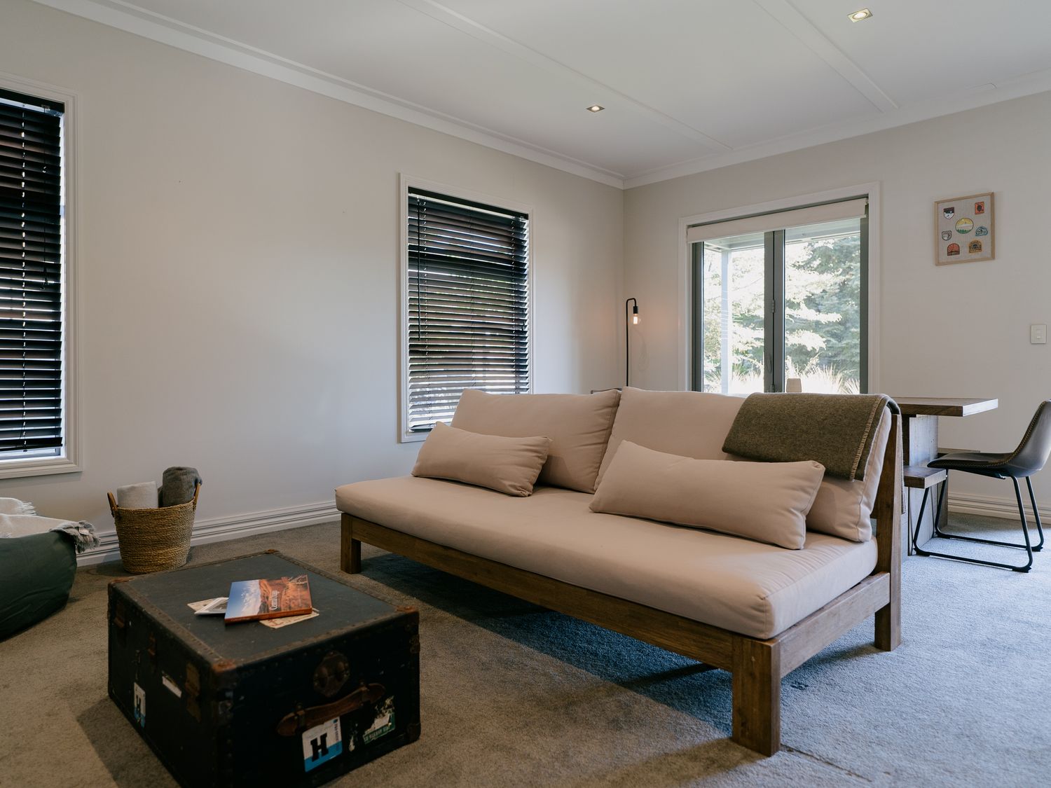 A living room with a beige sofa a black trunk coffee table and a dining table with chairs at Cardrona Valley Escape in Cardrona
