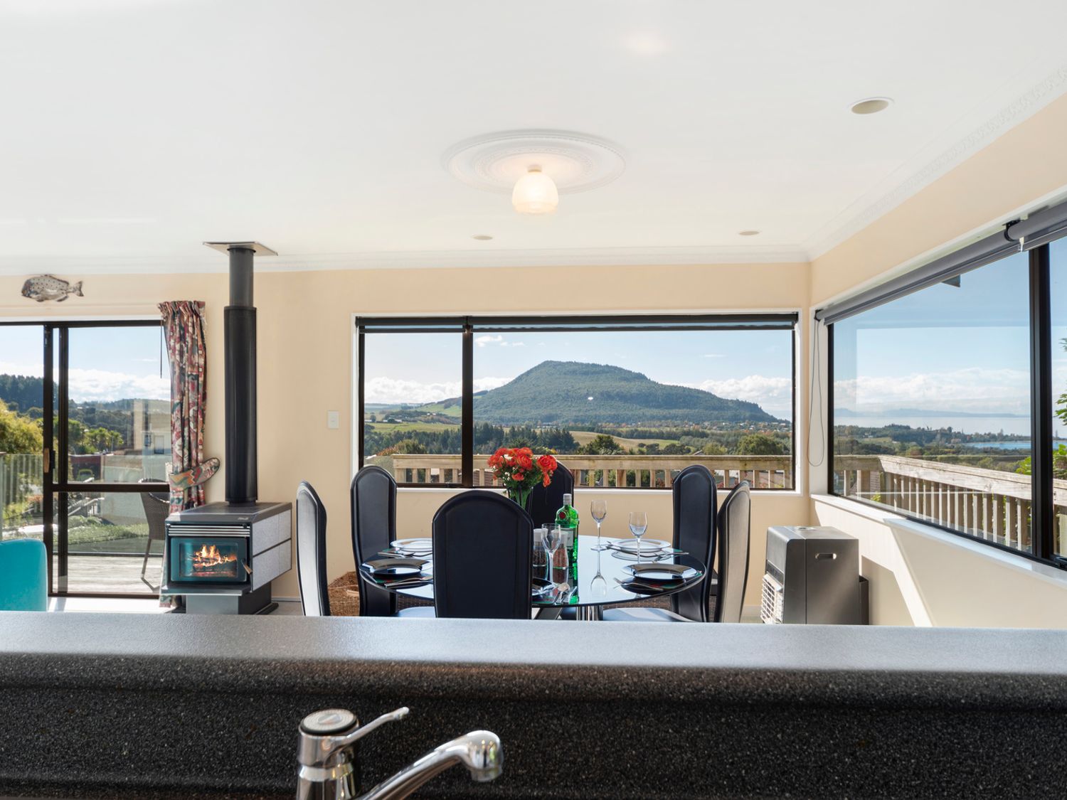 A dining area with a glass table set for six near windows showing a mountain view at Kuharua Lakeviews- Omori Holiday Home in Omori