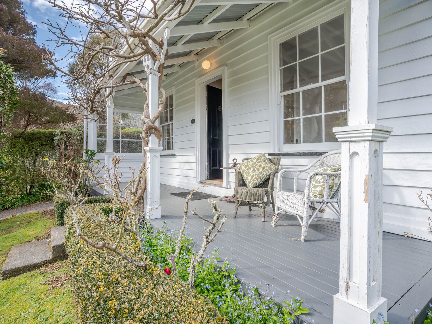 A porch with two chairs and cushions a small garden in front at Libeau Cottage - Akaroa Holiday Home in Akaroa