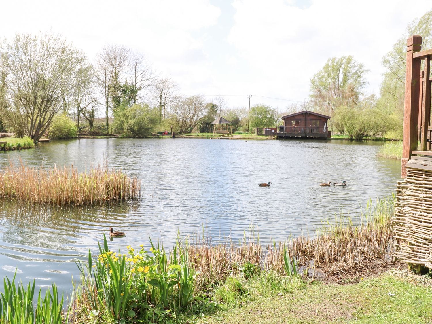 Wagtail Lodge in Badwell Ash in Suffolk. Lakeside lodge. Lovely views. Decking with hot tub and BBQ.