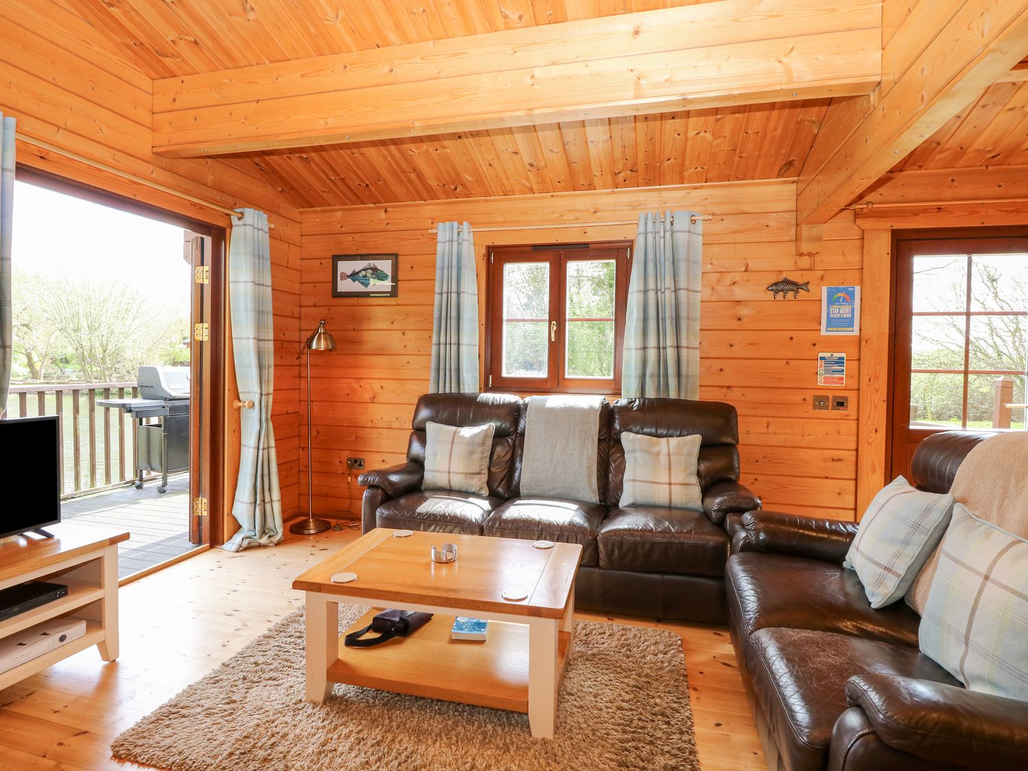 Woodpecker Lodge in Badwell Ash, Suffolk. Adults only. Decking with hot tub and BBQ. Lakeside lodge.