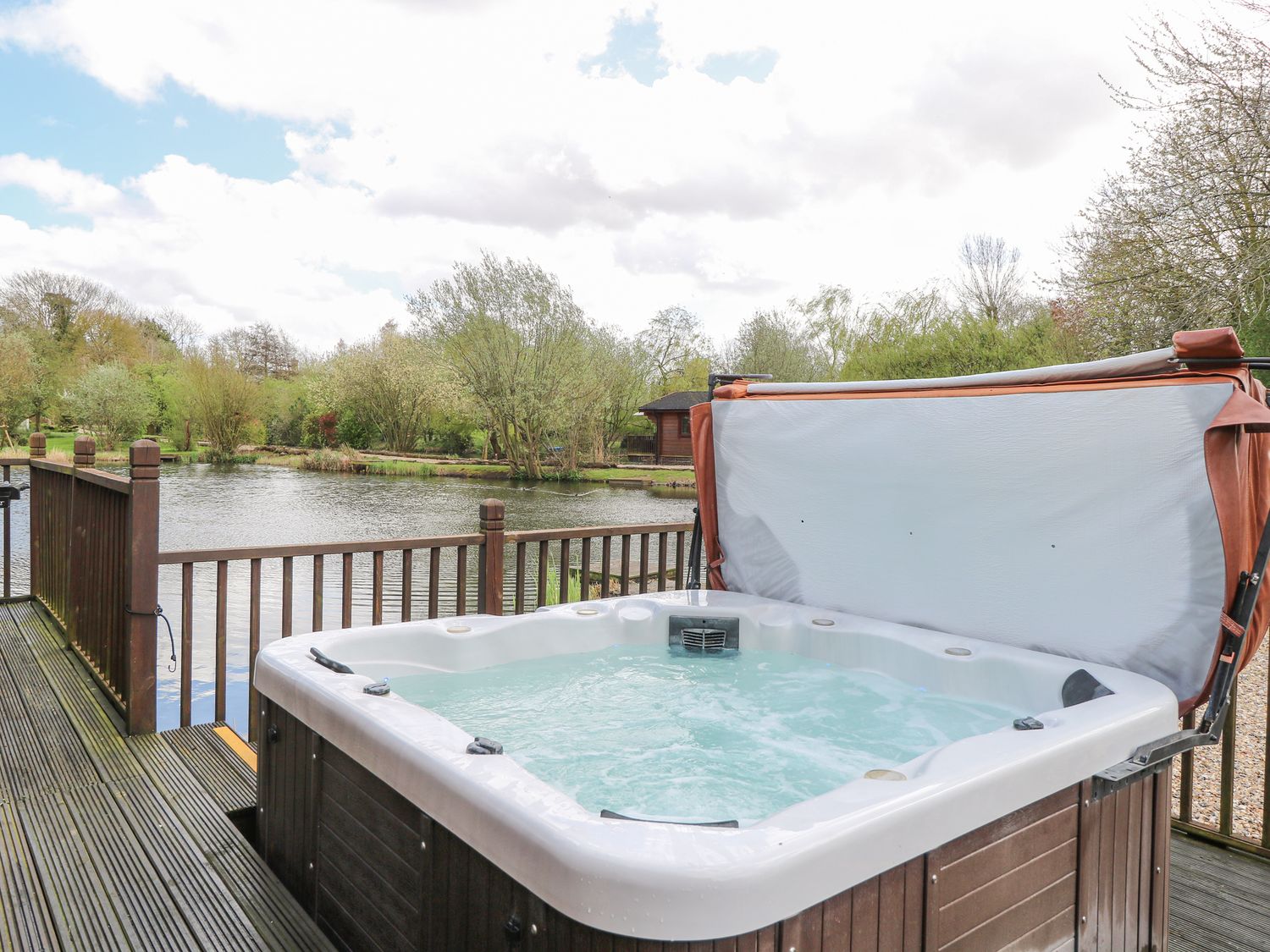 Woodpecker Lodge in Badwell Ash, Suffolk. Adults only. Decking with hot tub and BBQ. Lakeside lodge.