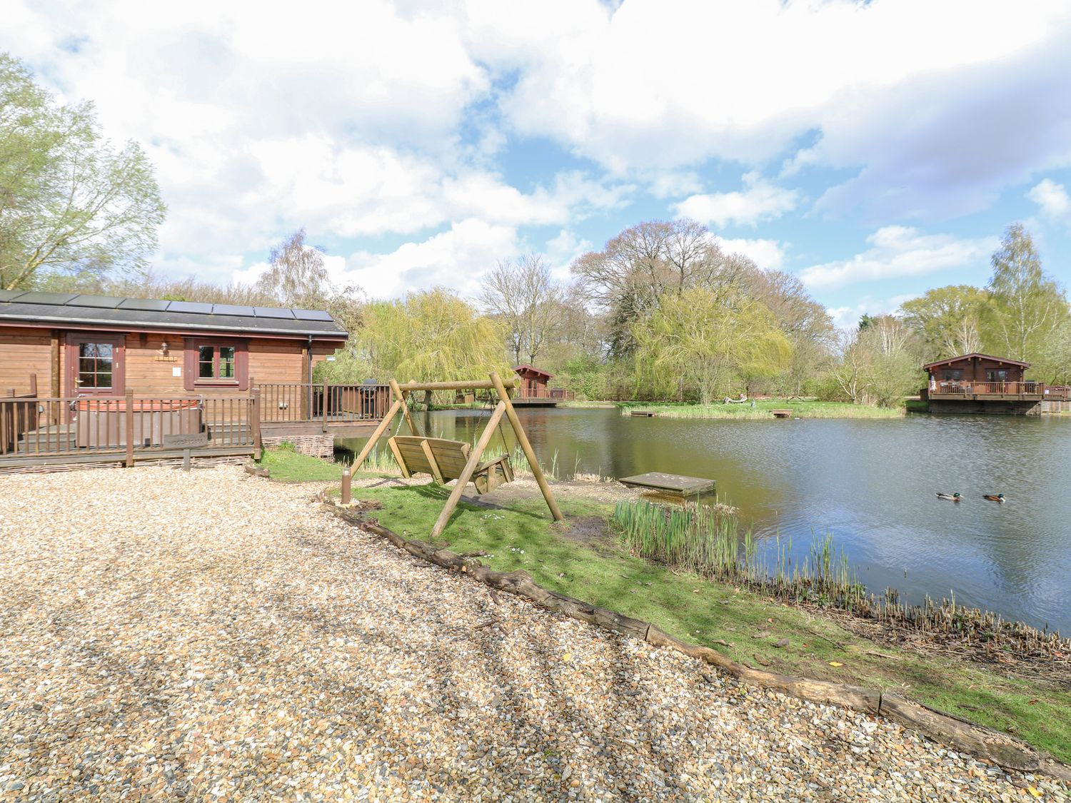 Woodpecker Lodge in Badwell Ash, Suffolk. Adults only. Decking with hot tub and BBQ. Lakeside lodge.