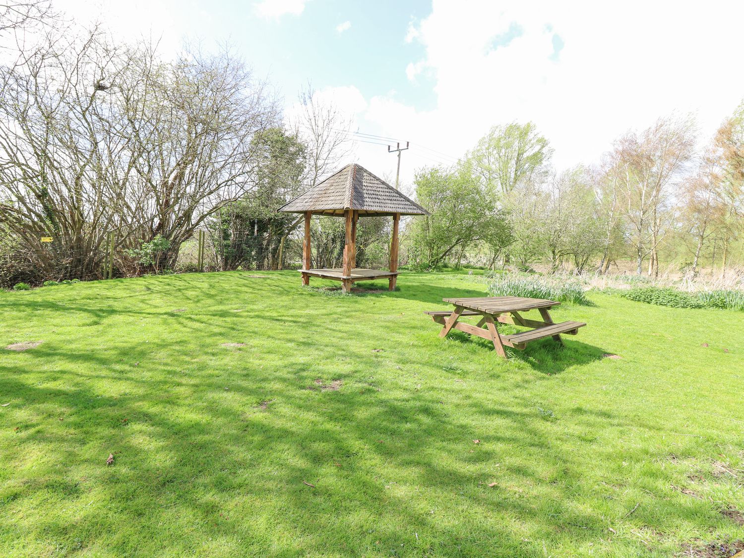 Woodpecker Lodge in Badwell Ash, Suffolk. Adults only. Decking with hot tub and BBQ. Lakeside lodge.