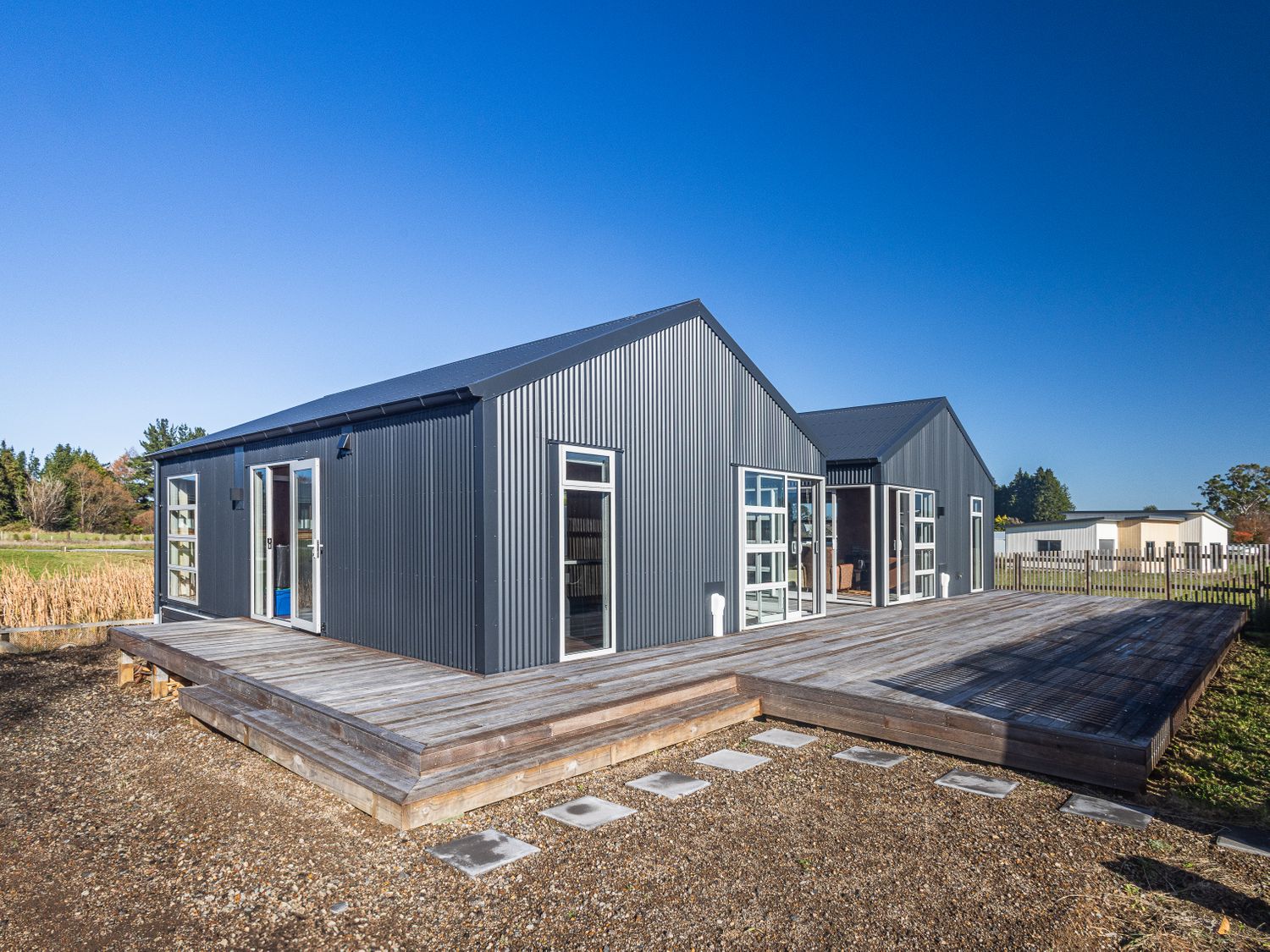 Exterior view of a dark gray metal house with multiple windows and doors on a wooden deck at Mountain Haus - Ohakune Holiday Home in Ohakune