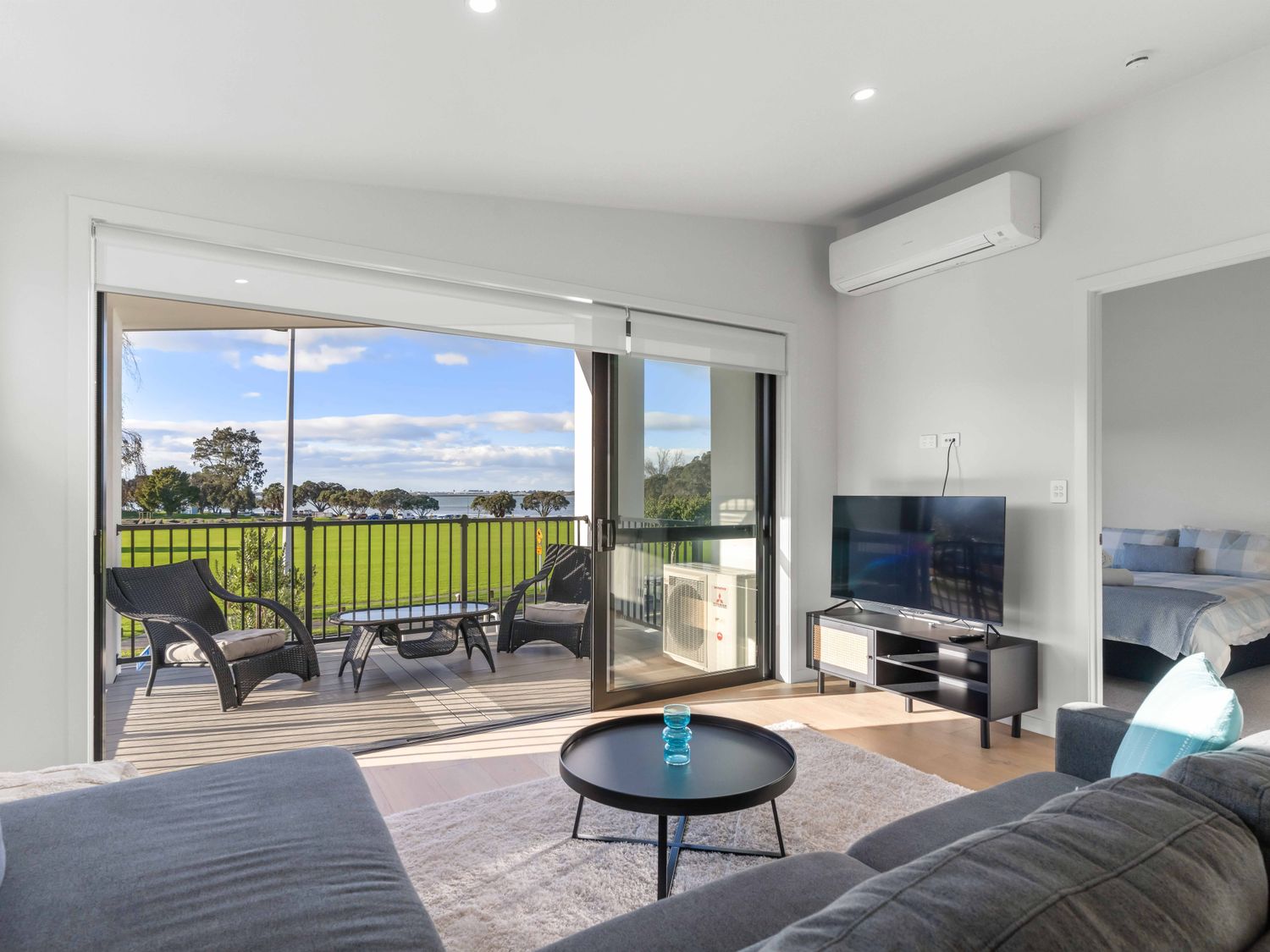 A living room with a television and sliding door at Tauranga Holiday Home in Tauranga