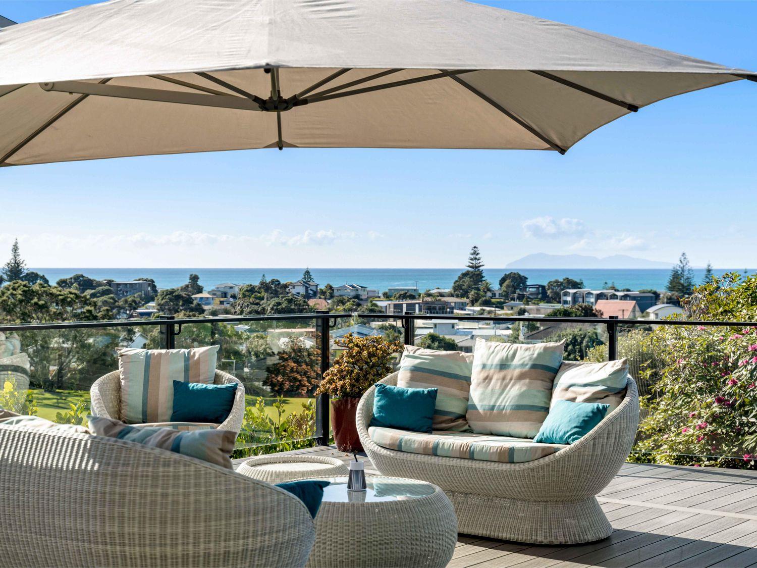 An outdoor seating area with wicker chairs and an umbrella at Island Views - Waihi Beach Holiday Home Waihi Beach