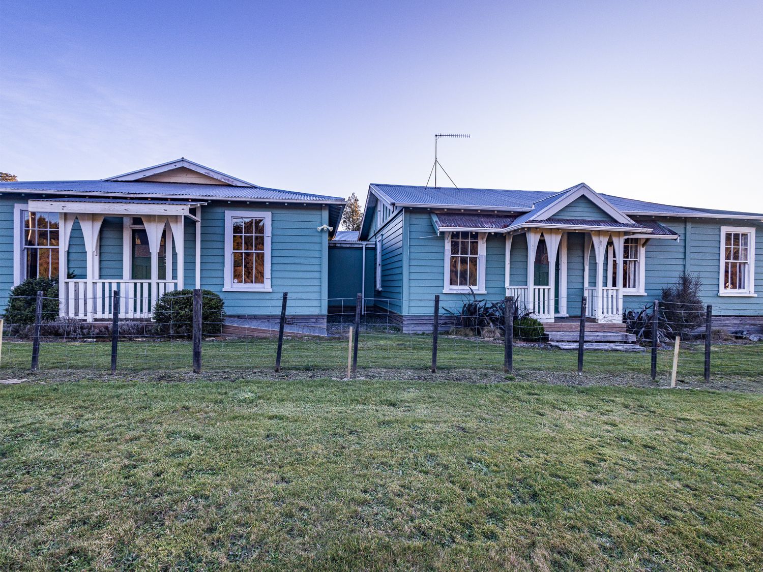 Two blue houses with a fence in front at Taylor Lodge Adventure Base -  Erua Holiday Home